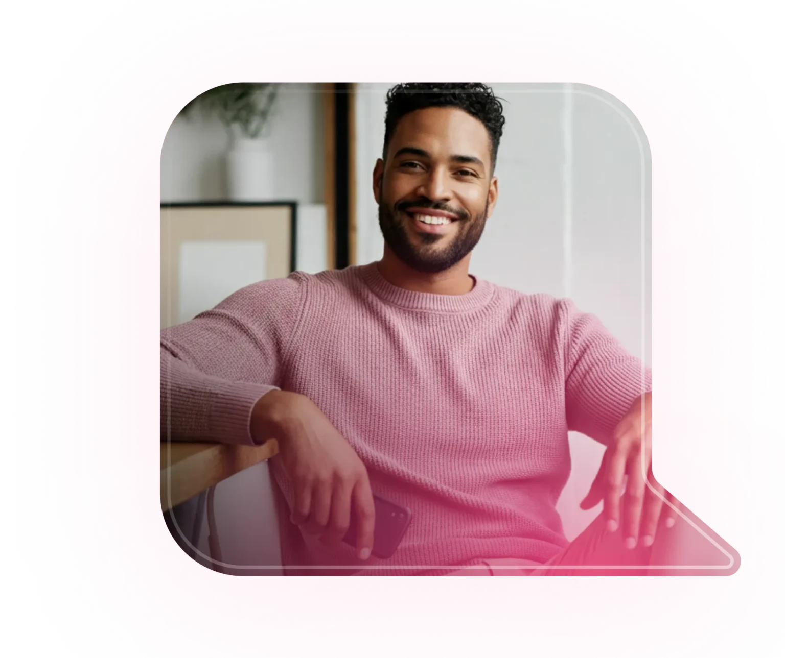 Homem moreno sorrindo usando camisa rosa com celular na mão